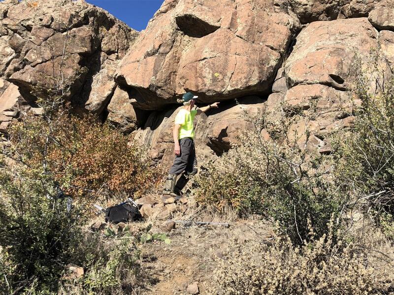 AES Volunteer, pointing to a natural rattlesnake den site